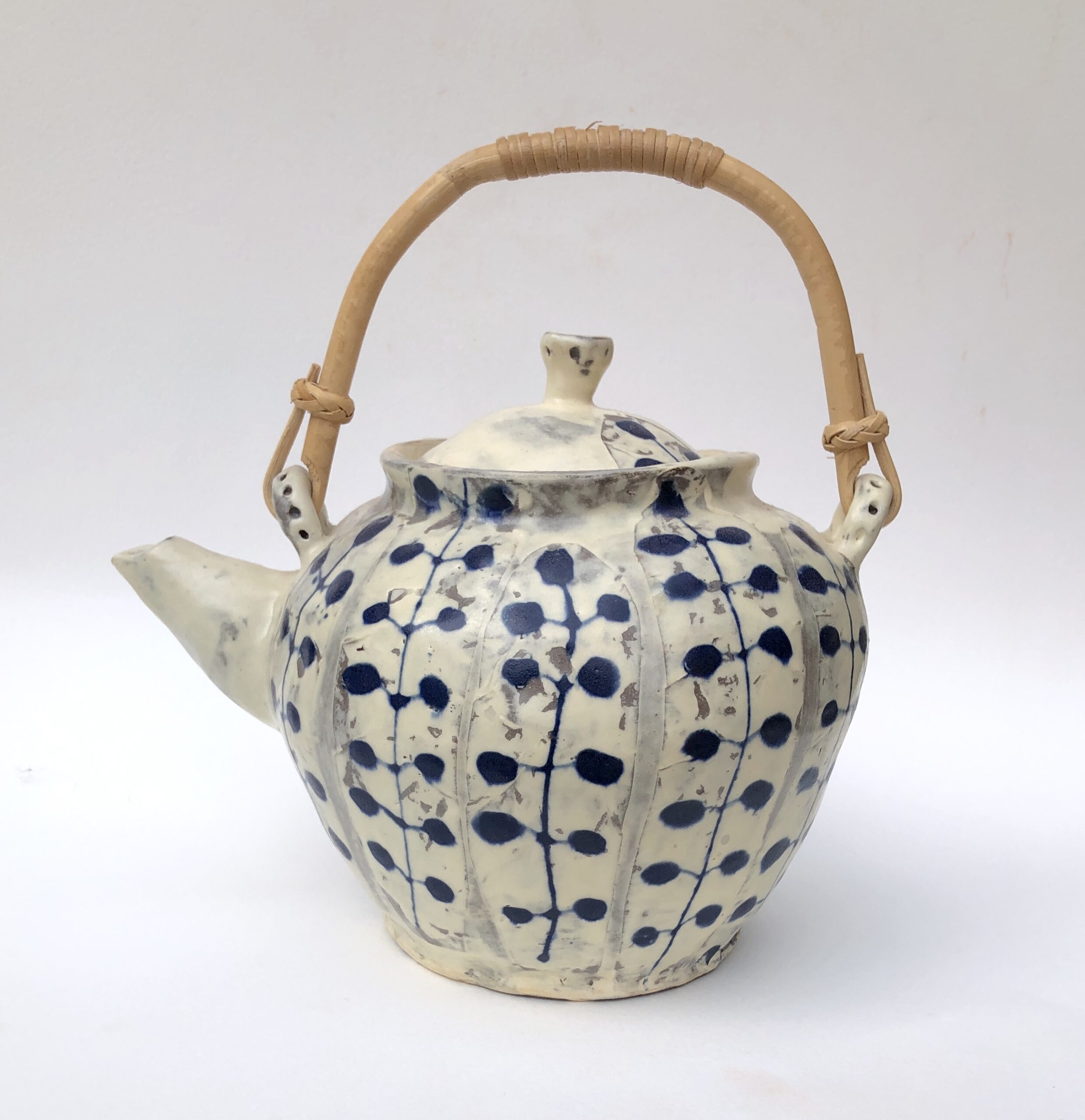 A Blue And White Teapot Featuring A Bamboo Handle