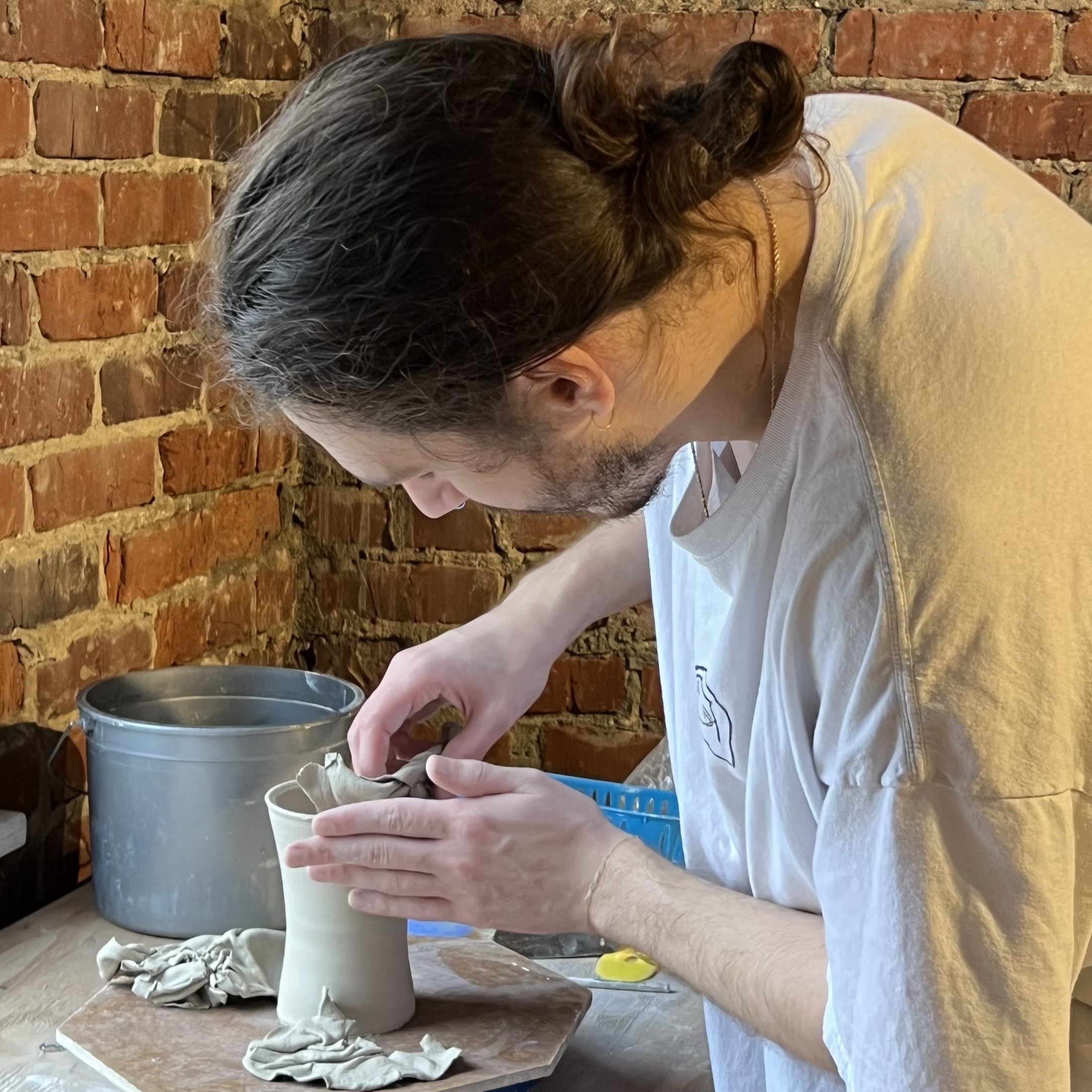 A Man Shapes A Pottery Vase On A Table