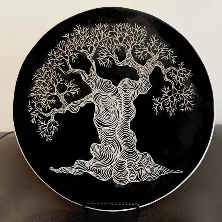 A Black And White Plate Featuring An Intricate Tree Design In The Center.