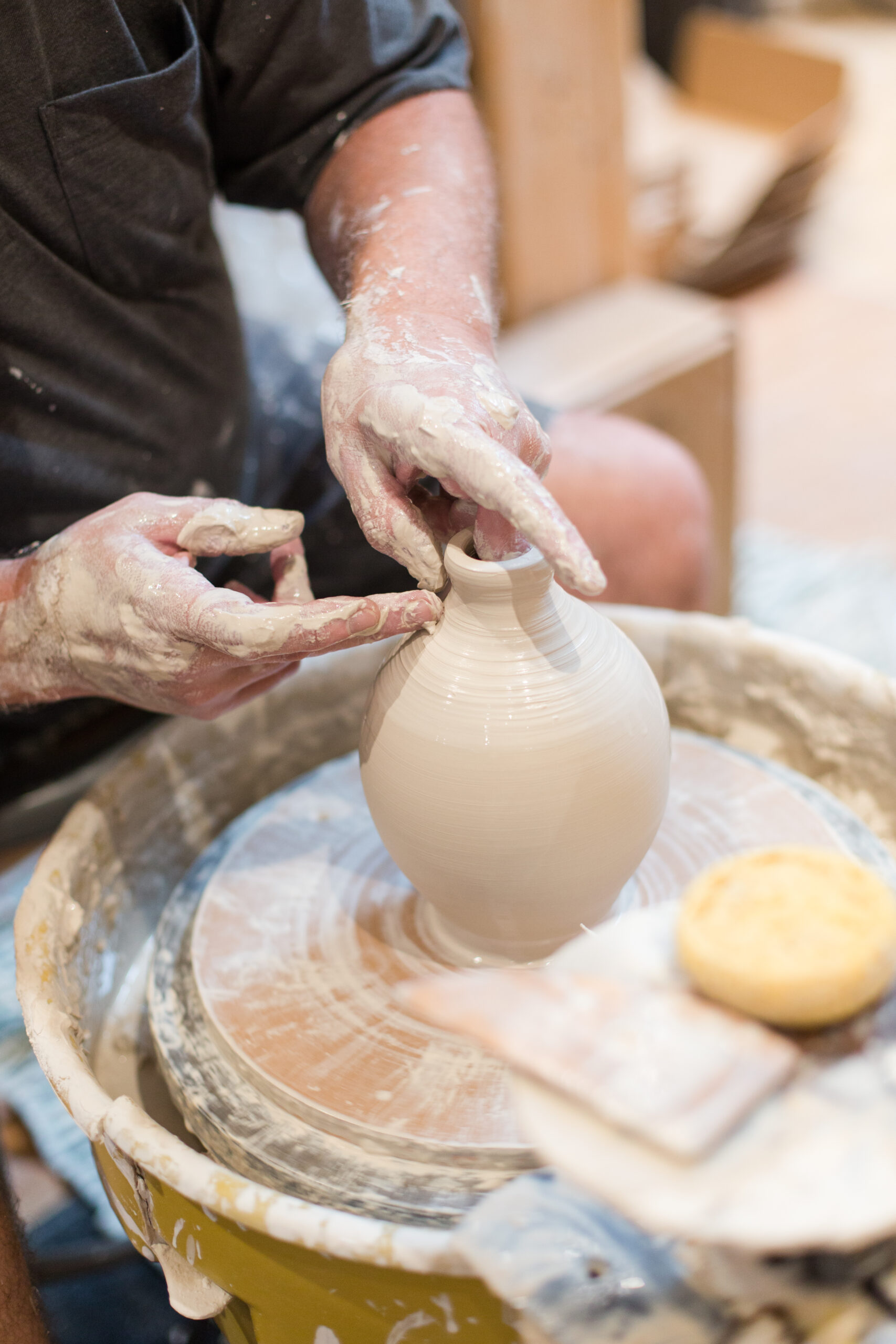 Focused On His Craft With Tools And Clay Surrounding Him.